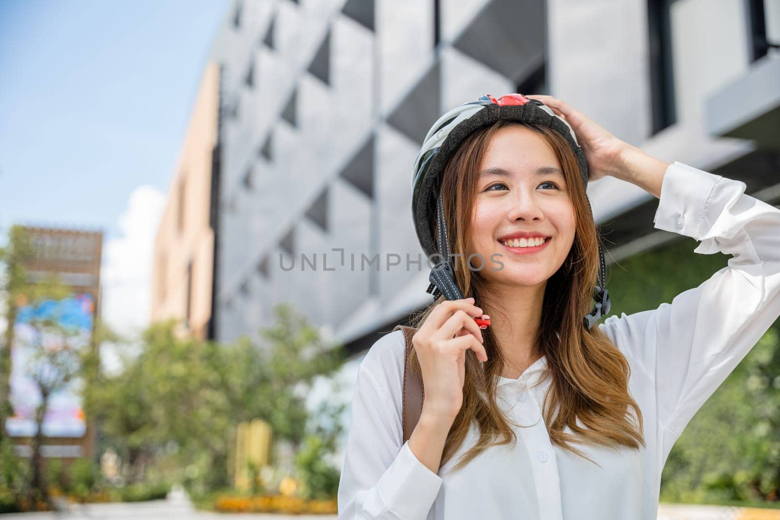 Close up smiling woman wearing helmet exercise outdoors with bicycle on street by Sorapop