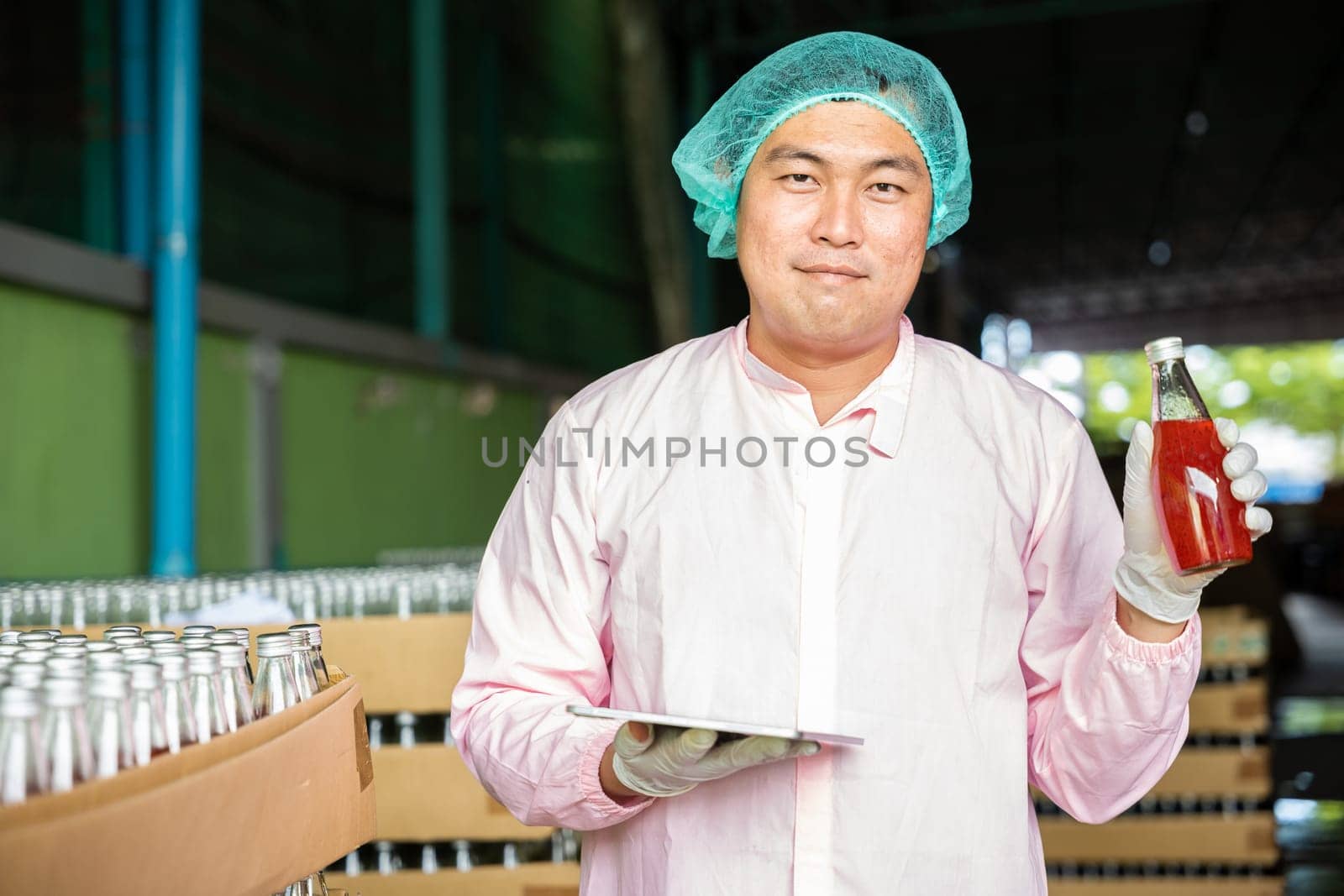 Inspector verifies bottled products on conveyor belt in beverage factory maintaining high quality by Sorapop