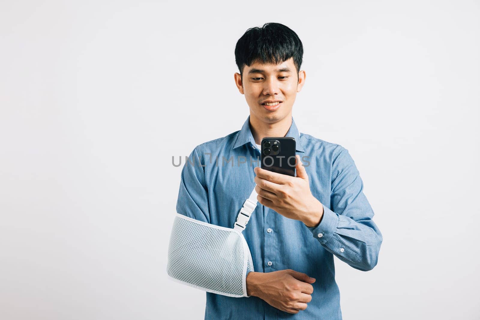 A man confidently smiles with a broken arm, using a splint and holding a smartphone by Sorapop