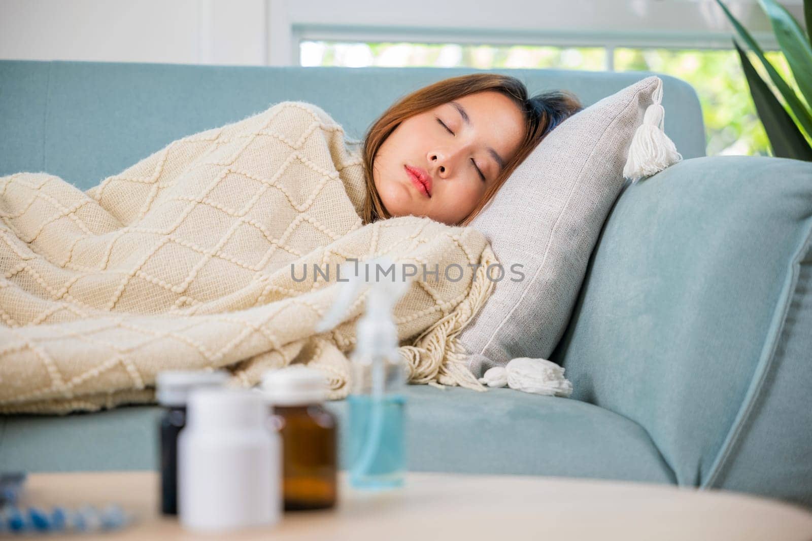 Asian beautiful female use pharmacy first aid kit box delivery service from hospital, Young woman tired sick she sleep and resting on sofa after take medicines pills in living room at home, healthcare