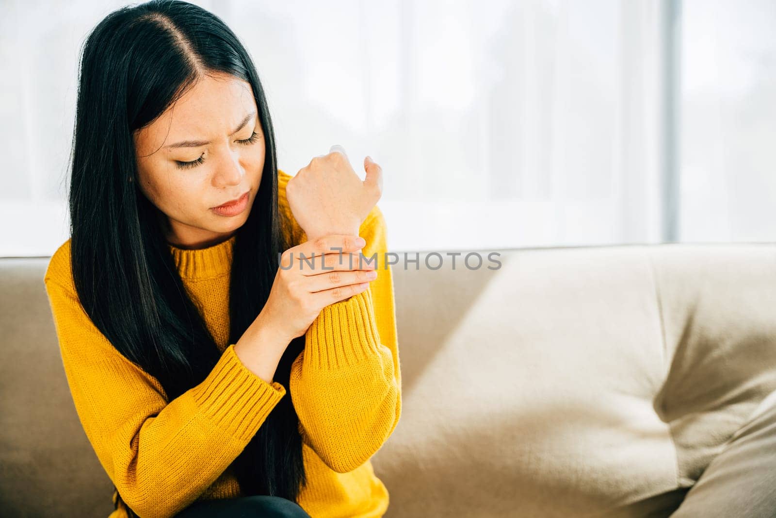 A woman holds her achy wrist indicating Carpal Tunnel Syndrome or wrist pain. Illustrating symptoms inflammation and discomfort in the hand's anatomy. Health care concept