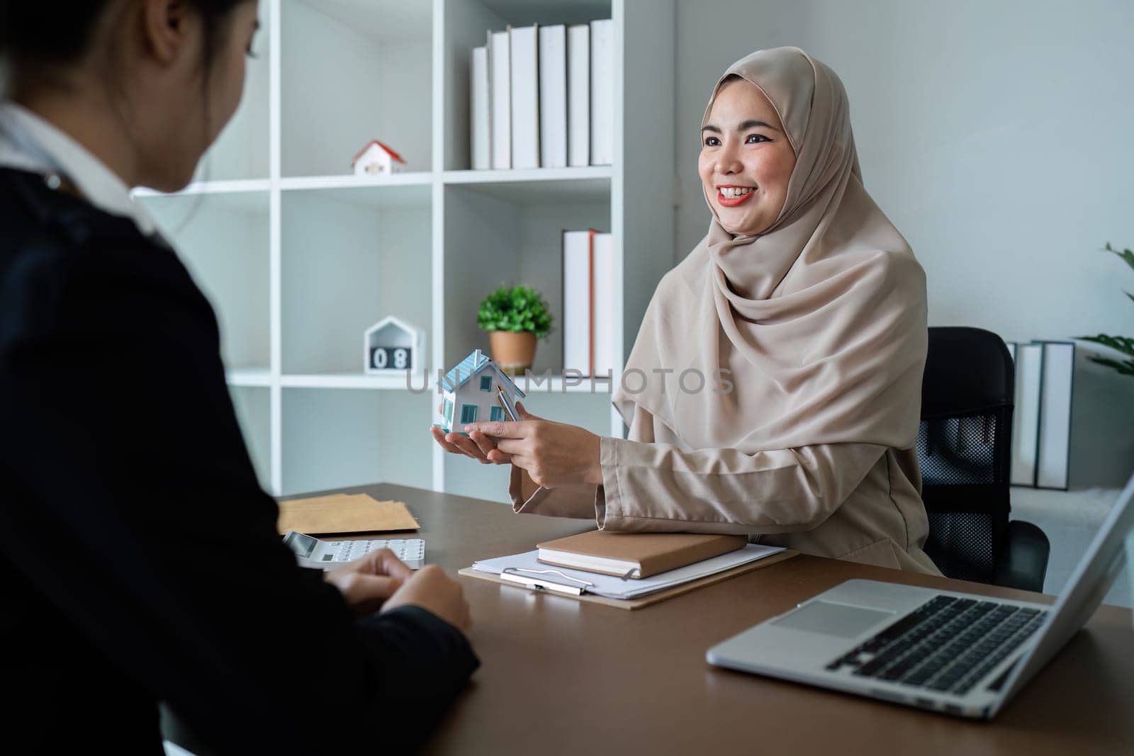 Muslim real estate agent talk about terms of home purchase agreement and ask the customer to sign document to make the contract legally by itchaznong