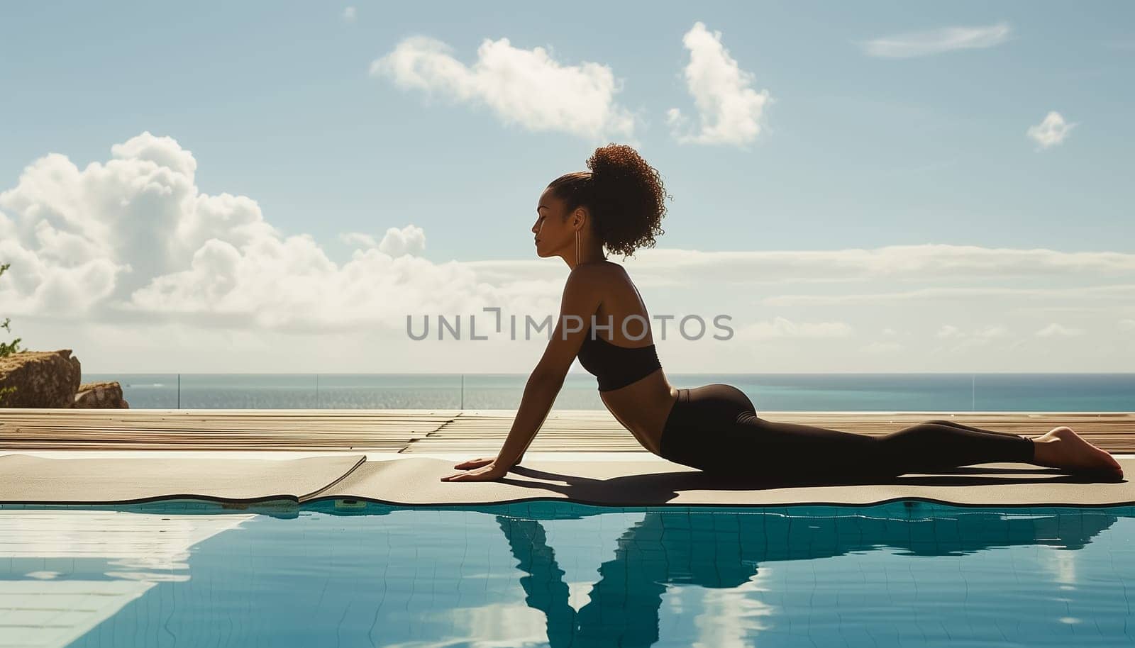 Young woman practicing yoga by a swimming pool with ocean in the background. by sarymsakov