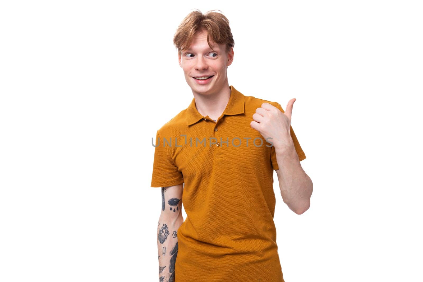 portrait of handsome young redhead caucasian male student with tattoo dressed in mustard t-shirt.