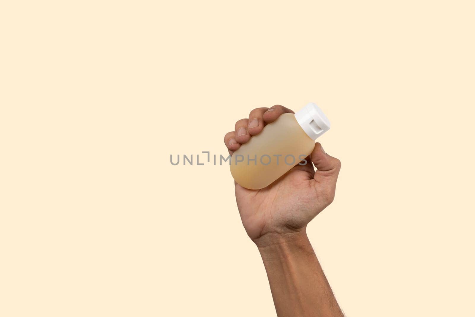 Black male hand holding shaampoo or gel container mockup on beige background. by TropicalNinjaStudio