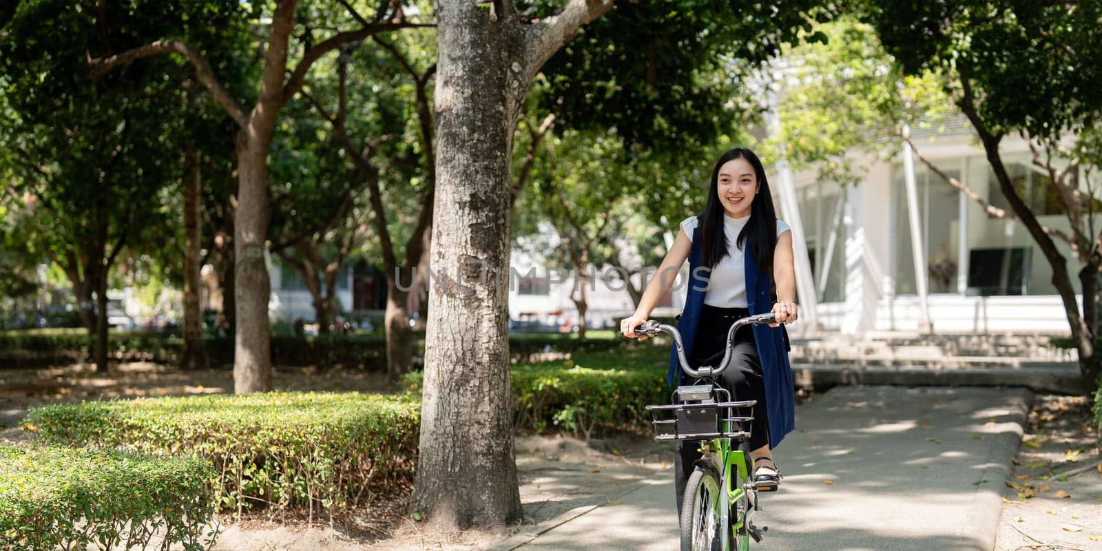 Eco friendly, Happy lifestyle asian beautiful young businesswoman riding bicycle go to office work at city street with bicycle in morning by nateemee