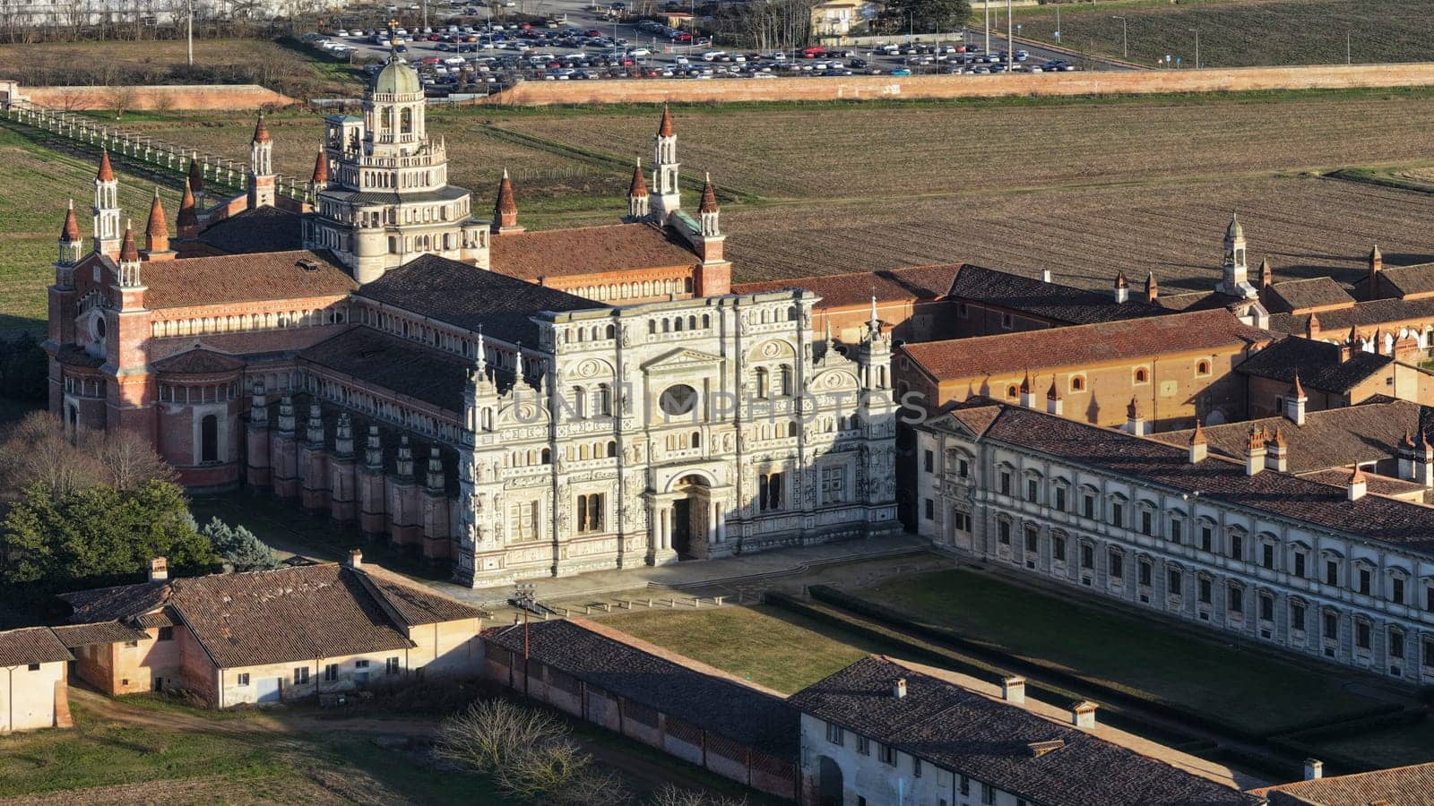 Drone shot over Certosa di Pavia monastery with lawn fields in Italy, Pavia