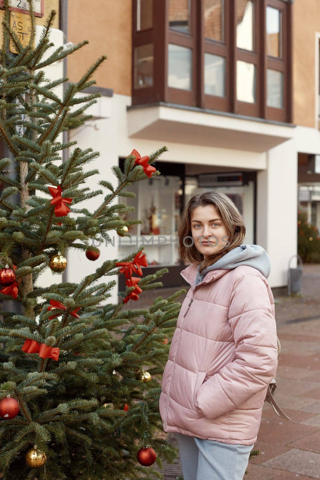 Elegance in the Old Town: Beautiful Woman Posing amidst the Festive Streets of Bietigheim-Bissingen, Germany . A beautiful girl stands on the street of the old European town of Bietigheim-Bissingen in Germany on Christmas Eve. City streets are decorated with Christmas trees and New Year's decorations, tourism, fashion, historical places, Europe