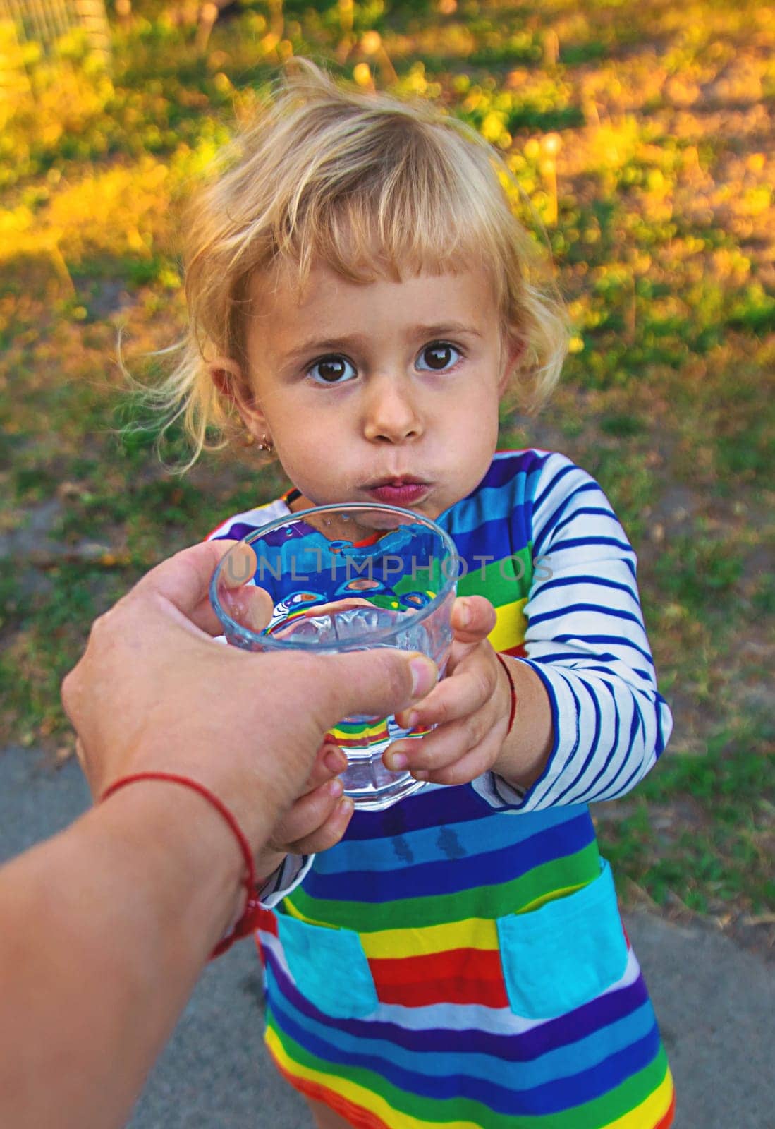 the father gives the child a glass of water. Selective focus. by yanadjana