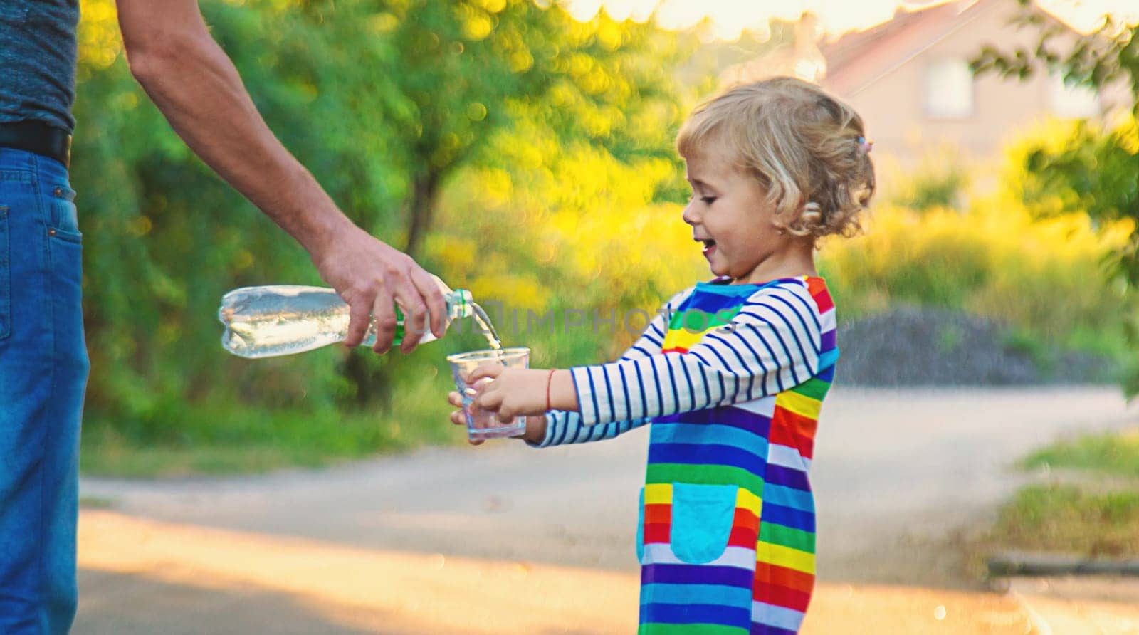 the father gives the child a glass of water. Selective focus. by yanadjana