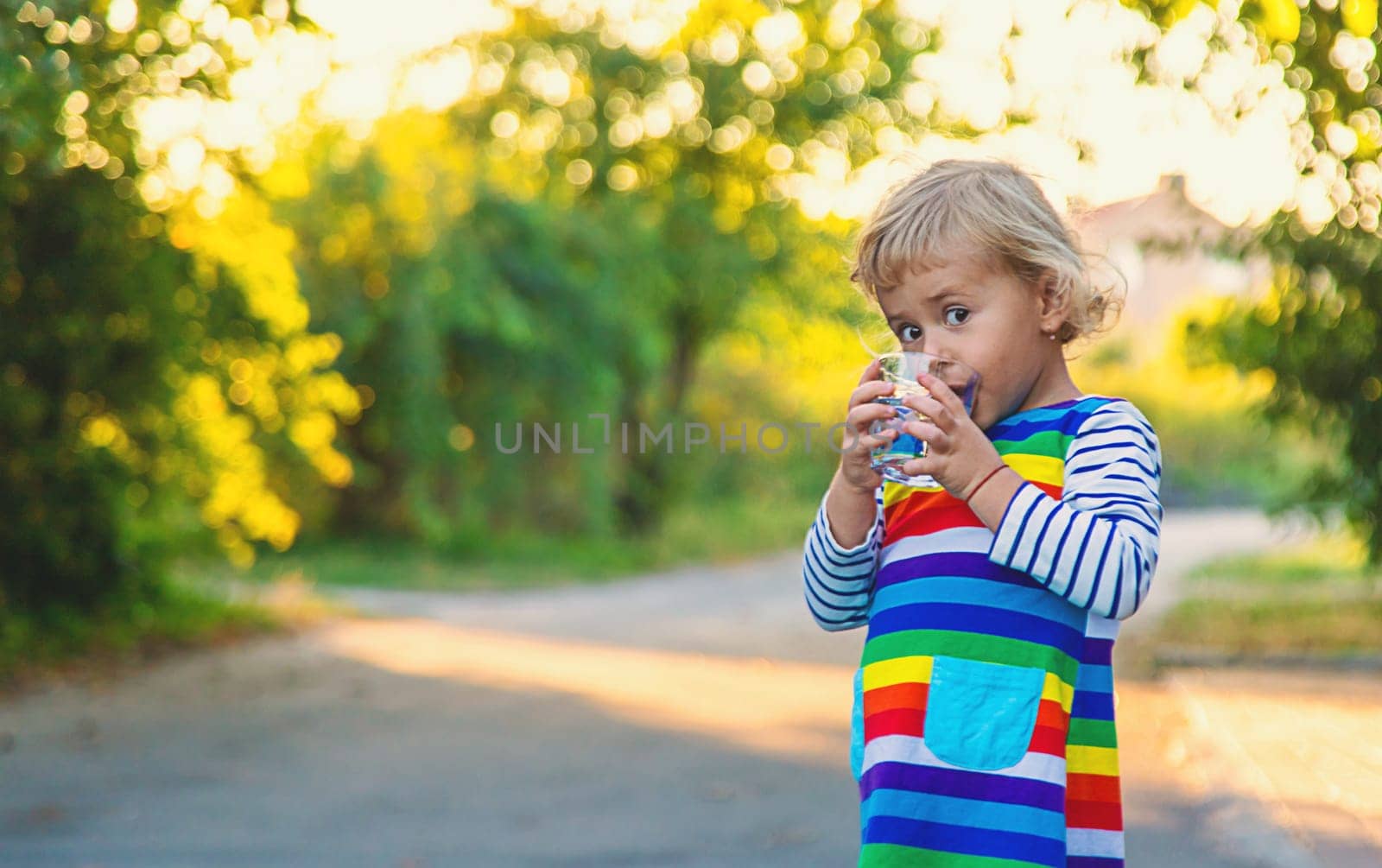 a child drinks water from a glass. Selective focus. Kid.