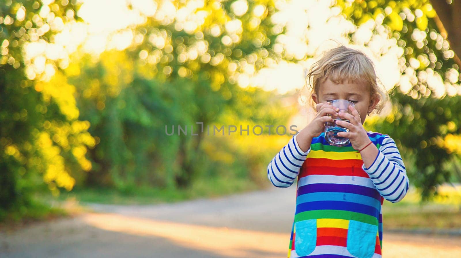 a child drinks water from a glass. Selective focus. Kid.