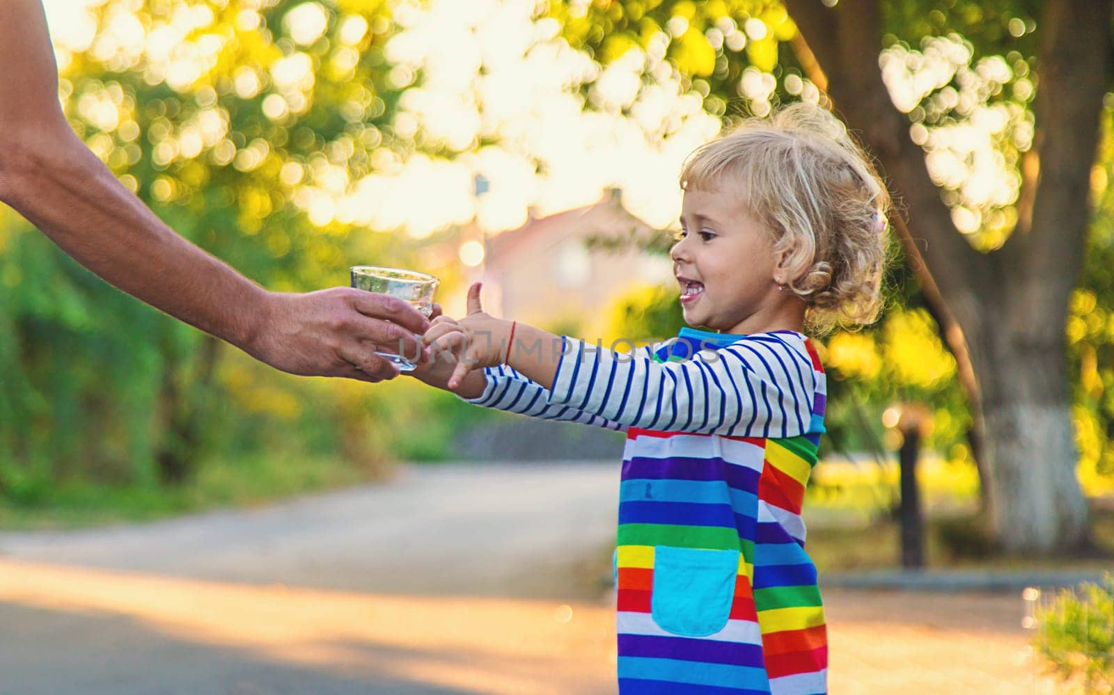 the father gives the child a glass of water. Selective focus. by yanadjana