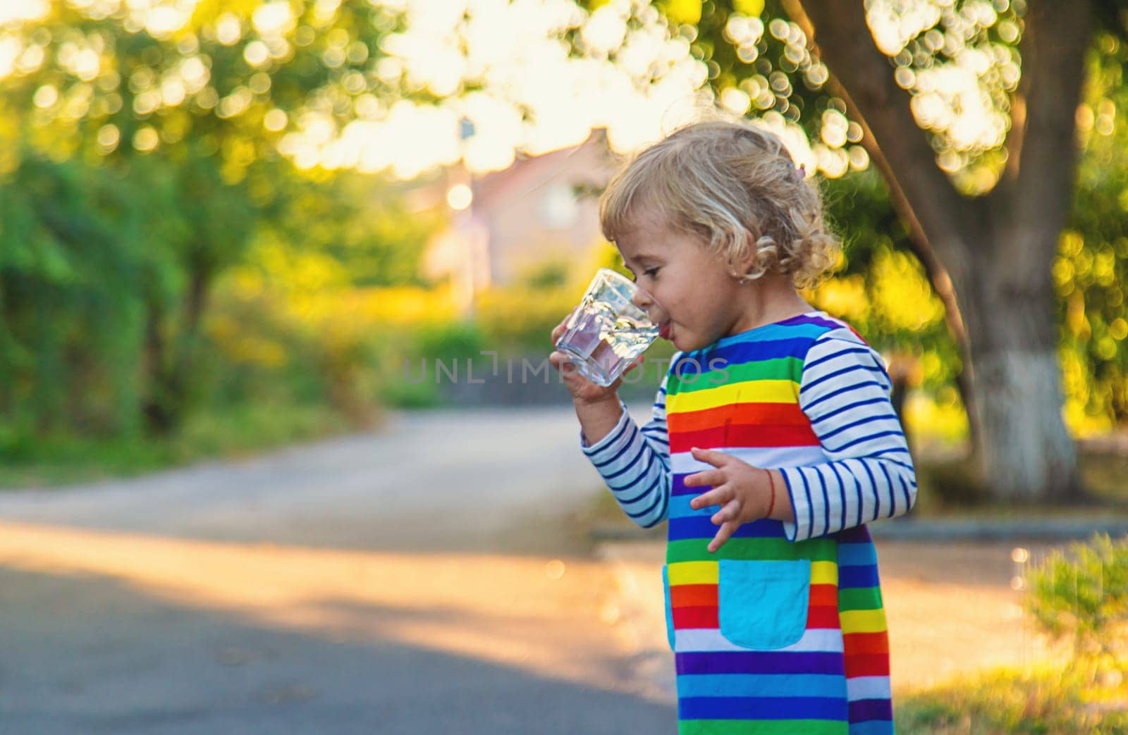 a child drinks water from a glass. Selective focus. Kid.