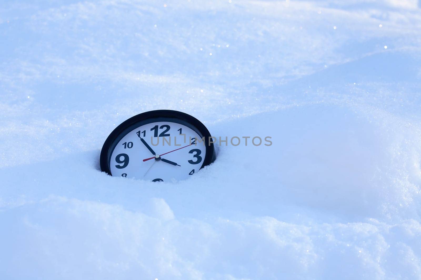 Clocks in the snow on the background of a winter landscape