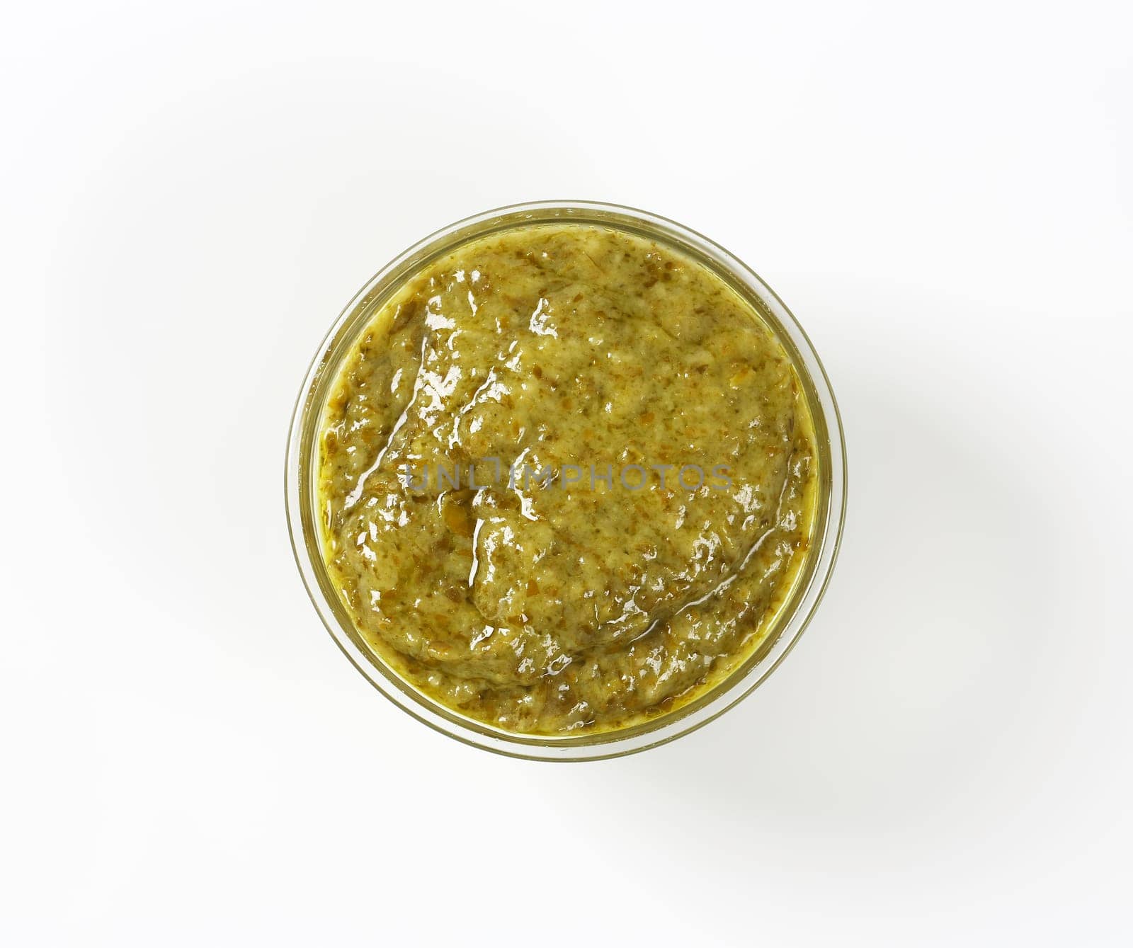 Basil pesto in glass bowl on white background