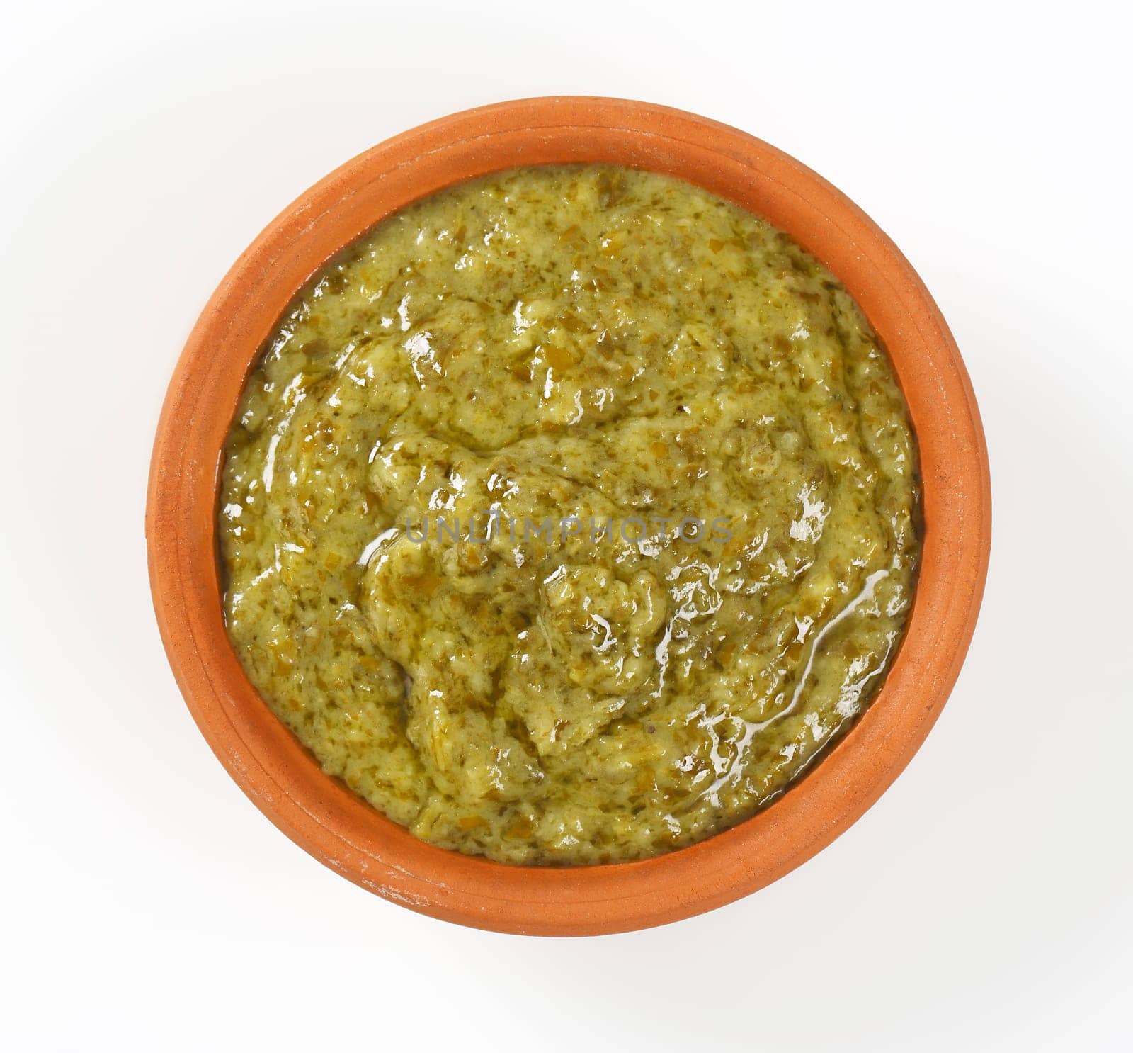 Basil pesto in terracotta bowl on white background