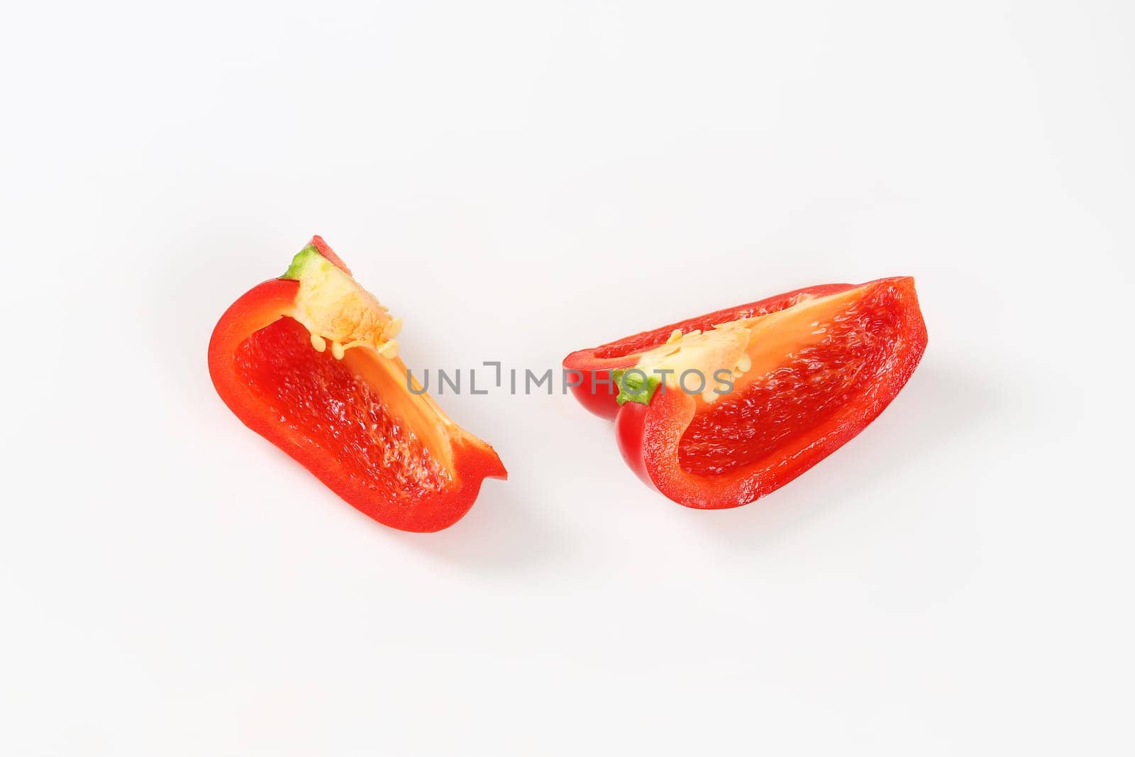 Two red bell pepper quarters on white background