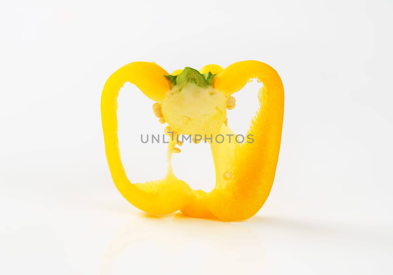 Slice of yellow bell pepper (cross section) on white background