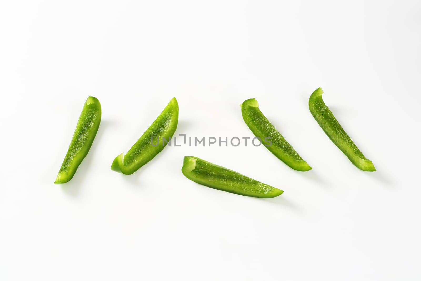 Thin slices of fresh green pepper on white background