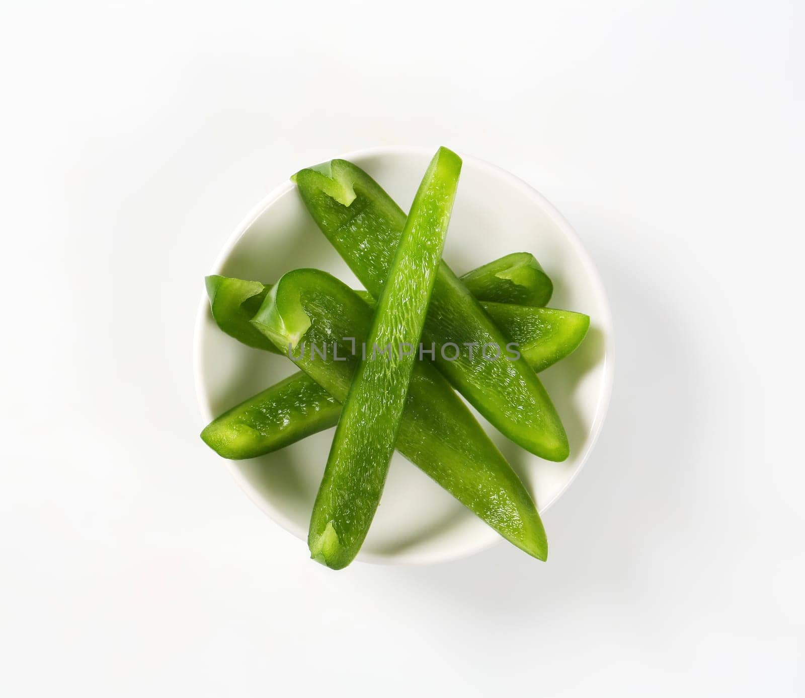 Thin slices of fresh green pepper in white bowl
