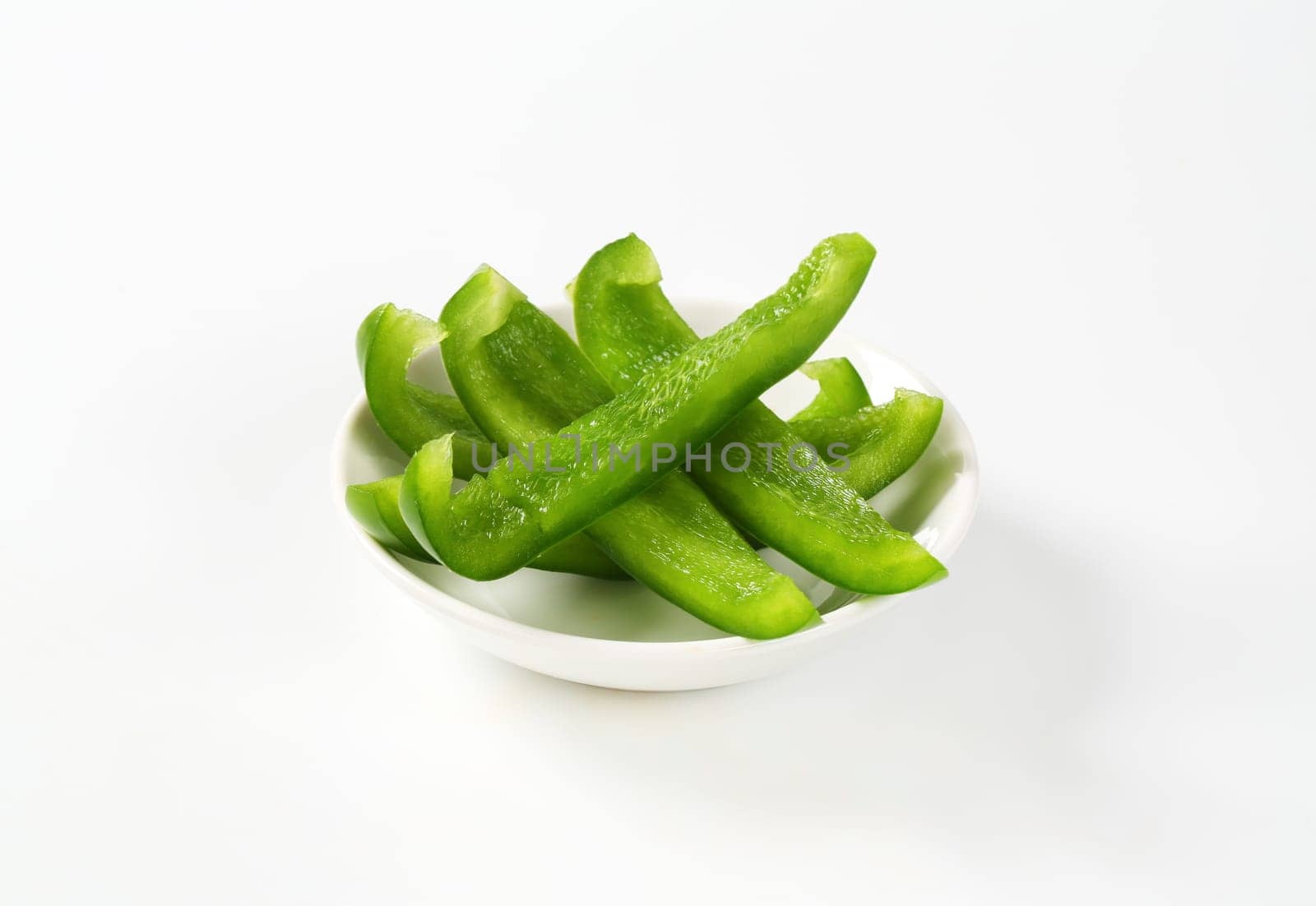 Thin slices of fresh green pepper in white bowl