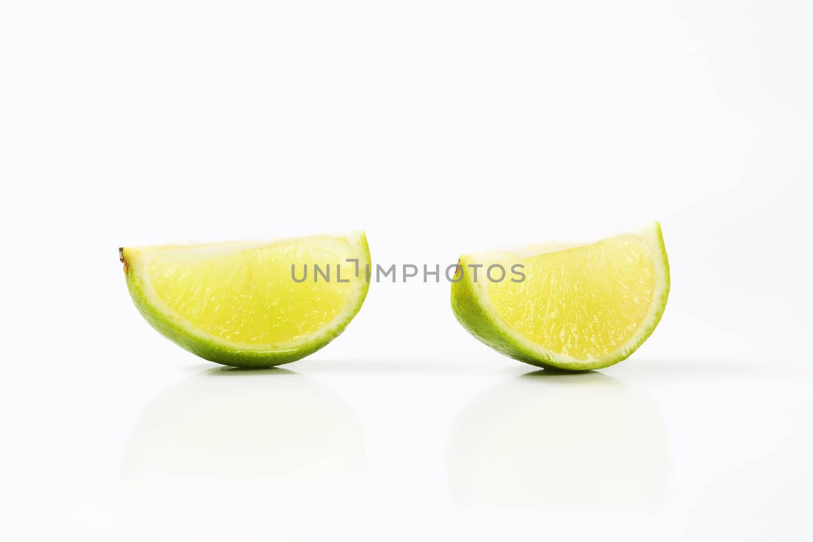 Two lime fruit quarters on white background
