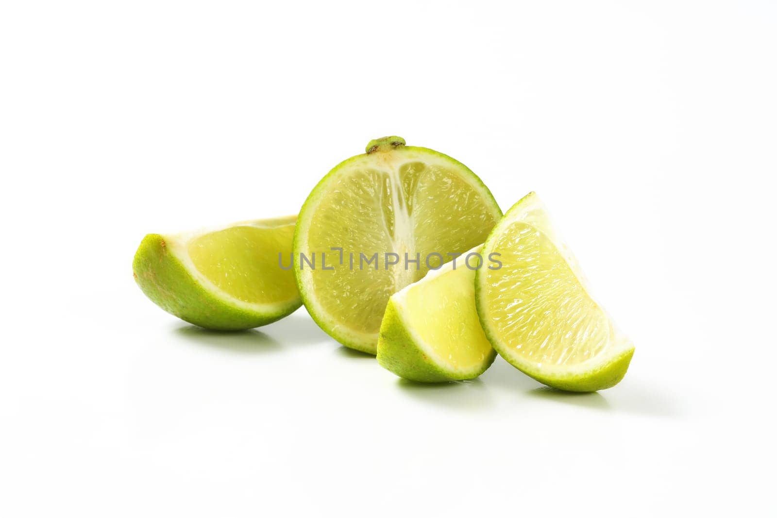 Half and wedges of fresh lime fruit on white background