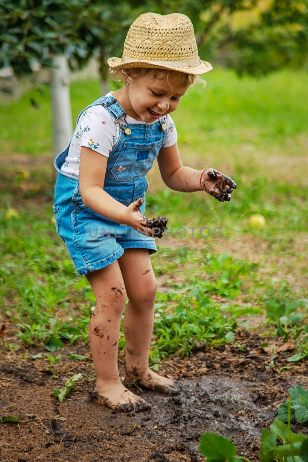 a child in the dirt in the garden holds the soil in his hands. Selective focus. by yanadjana