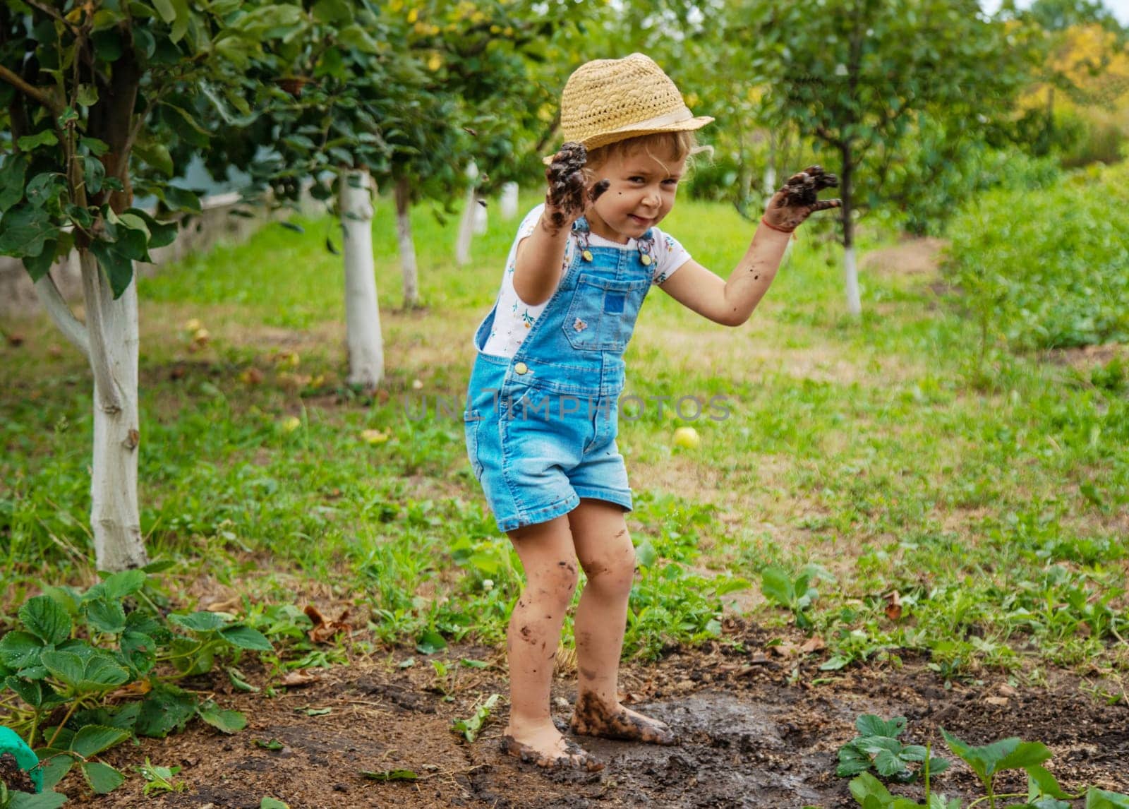 a child in the dirt in the garden holds the soil in his hands. Selective focus. by yanadjana