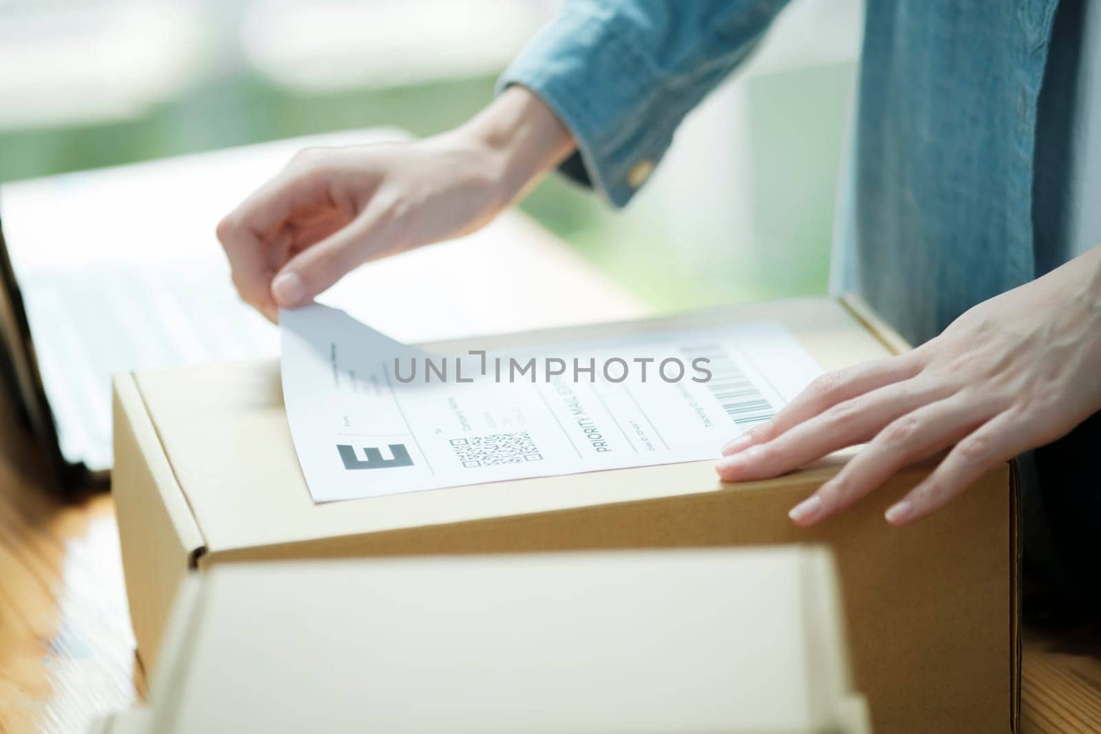 Attaching shipping label to a parcel. E-commerce business shipment preparation. Close-up of package labeling process.