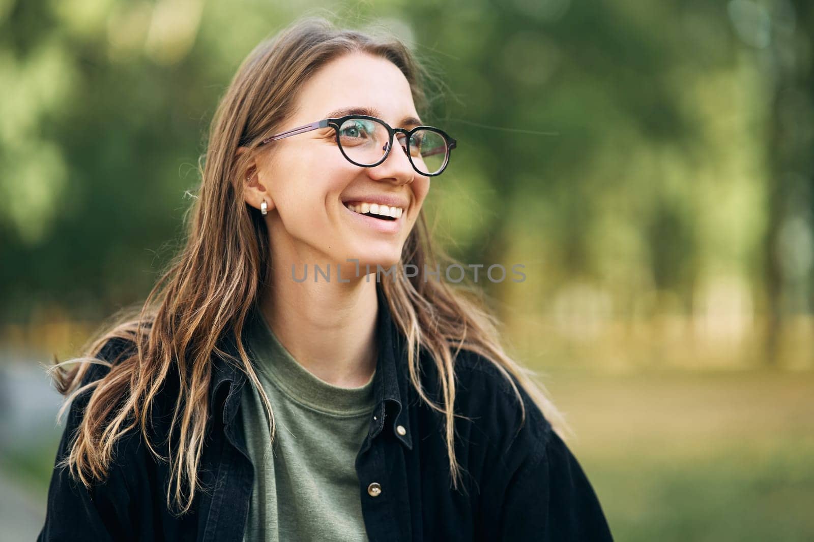 Portrait of a smiling young girl with glasses in the park by driver-s