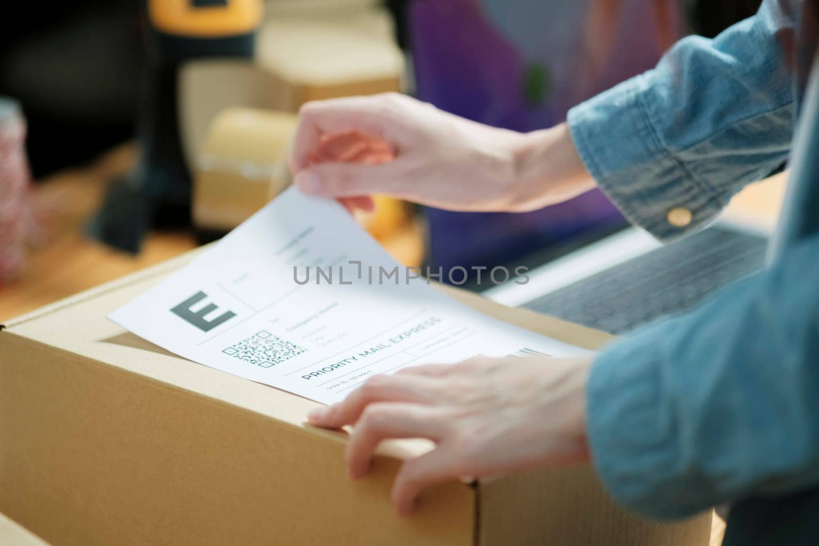 Attaching shipping label to a parcel. E-commerce business shipment preparation. Close-up of package labeling process.