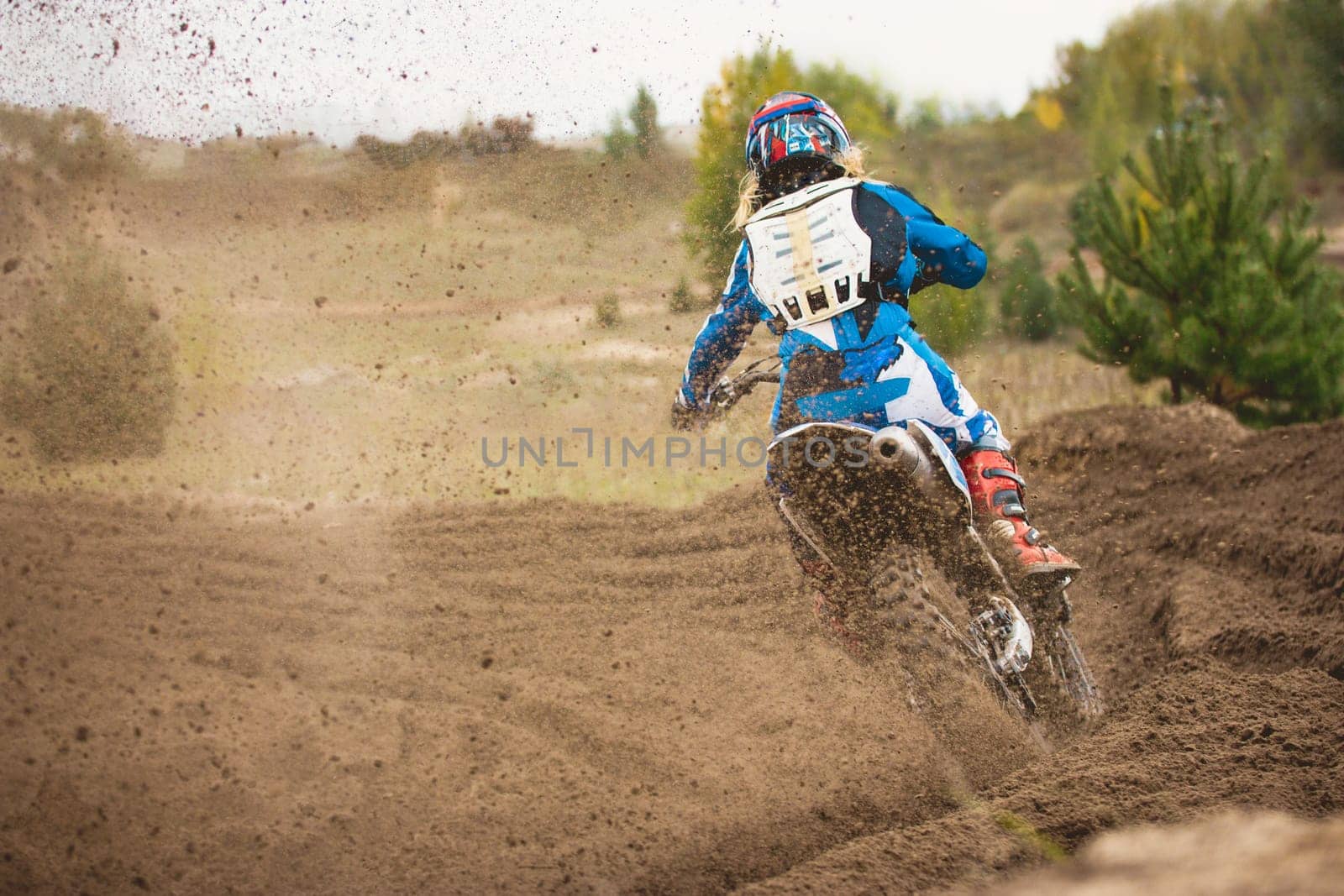 Moto cross - MX girl biker at race in Russia - a sharp turn and the spray of dirt, rear view, telephoto