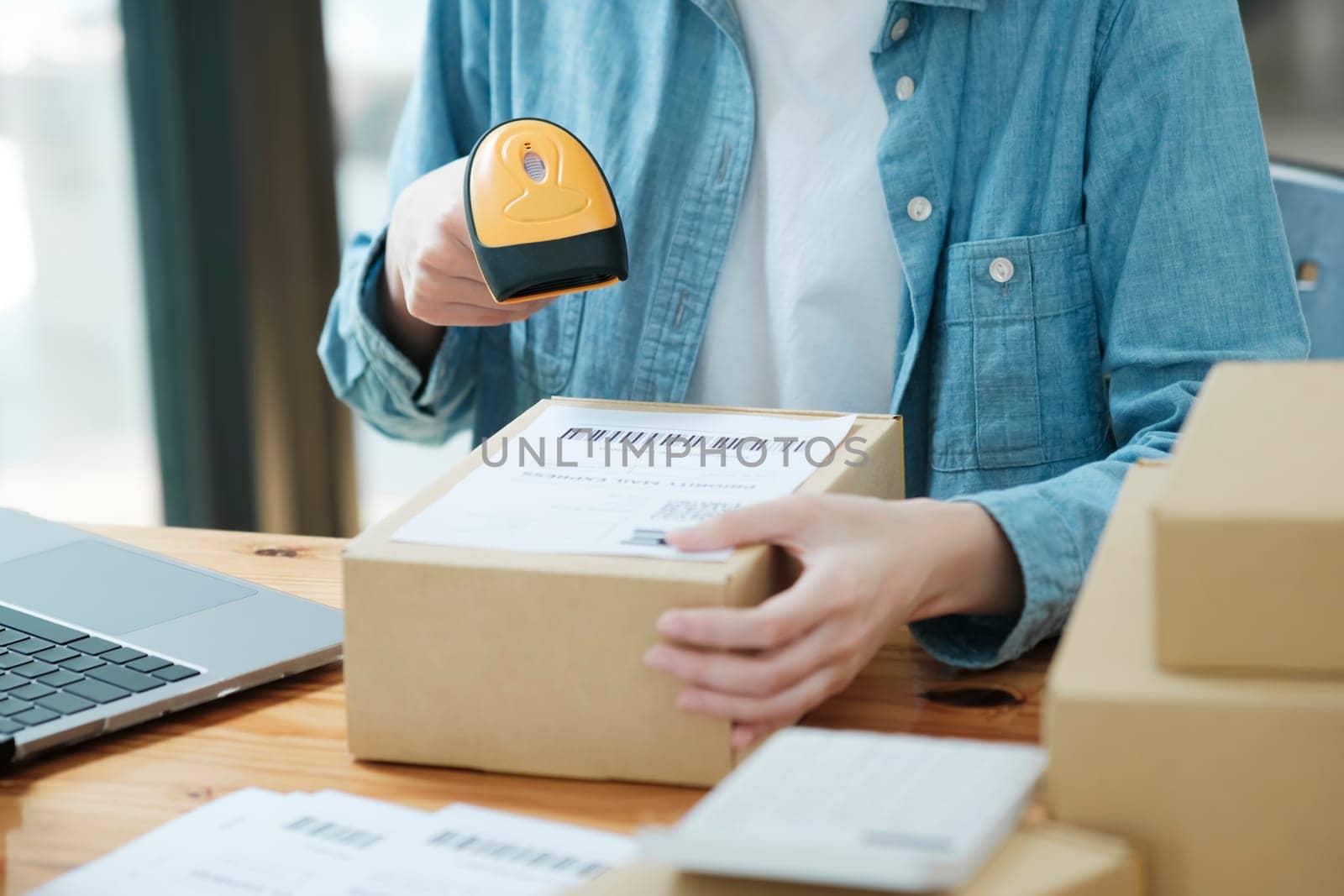 Scanning barcode on shipping label with handheld scanner. Order processing in e-commerce business. Package tracking and management concept.