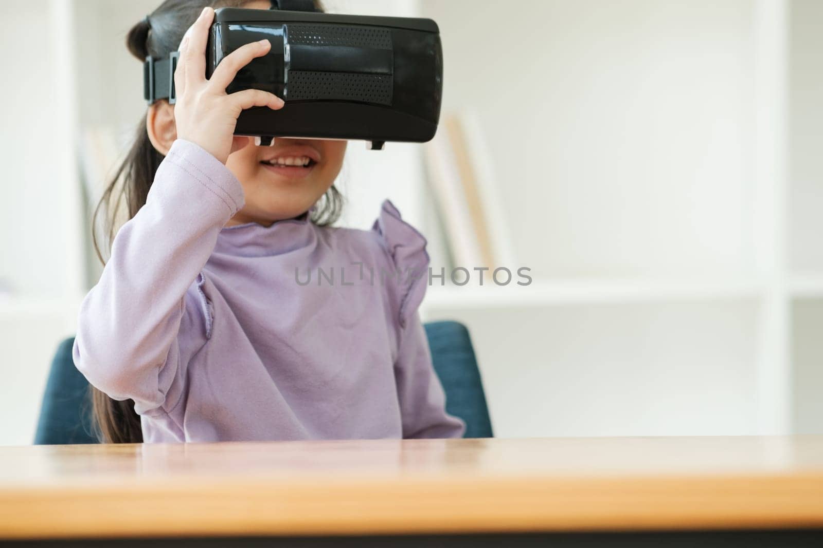 An elementary aged girl uses a virtual reality headset to enhance learning experience with excitement. Marketing for VR products, educational technology content.