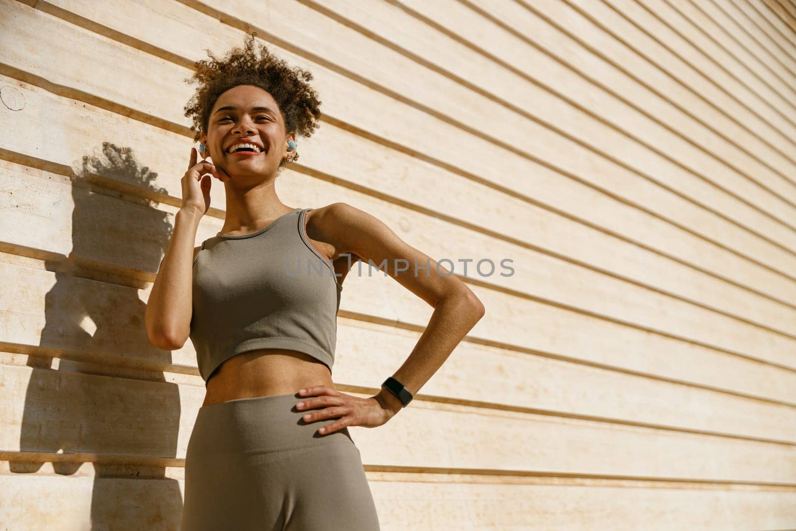 Smiling female athlete in sportswear have a rest after morning jogging outside and listen music by Yaroslav_astakhov