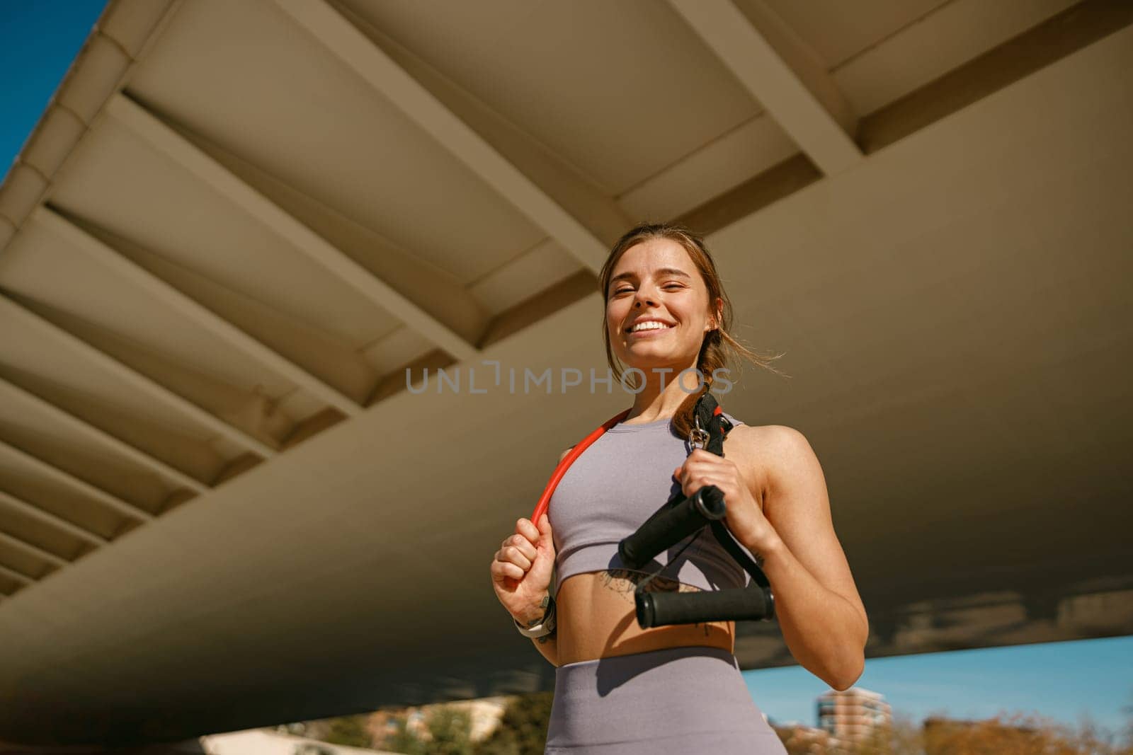 Beautiful athletic woman with a resistance band slung around her neck standing outdoors