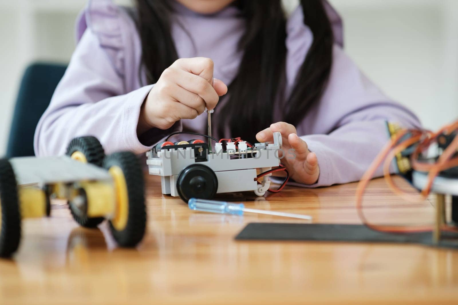 Asian girl concentrating on building a robot, embodying STEM education.