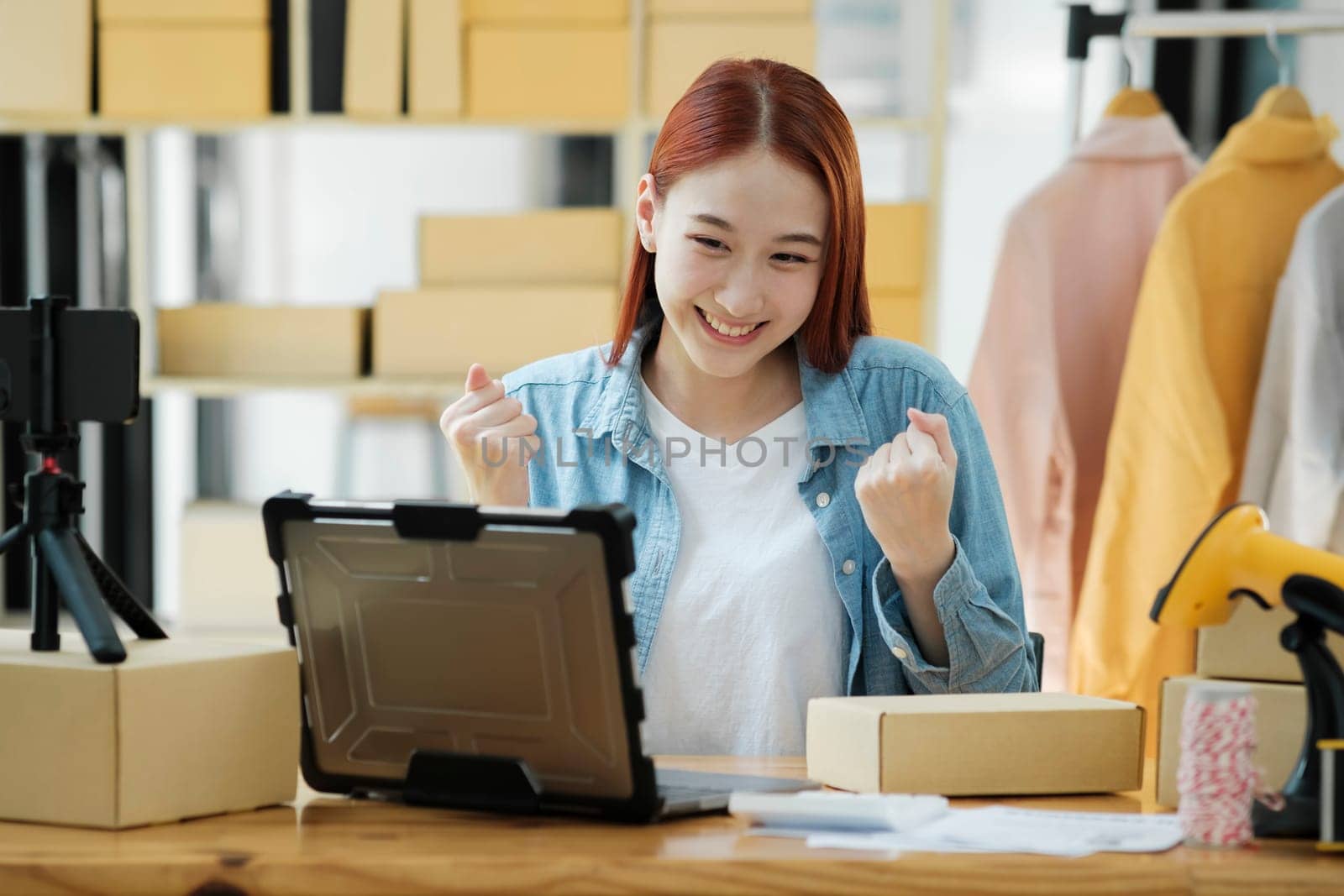 Successful small business owner celebrating a sale. E-commerce and online shopping success. Happy female entrepreneur celebrating a successful sale.