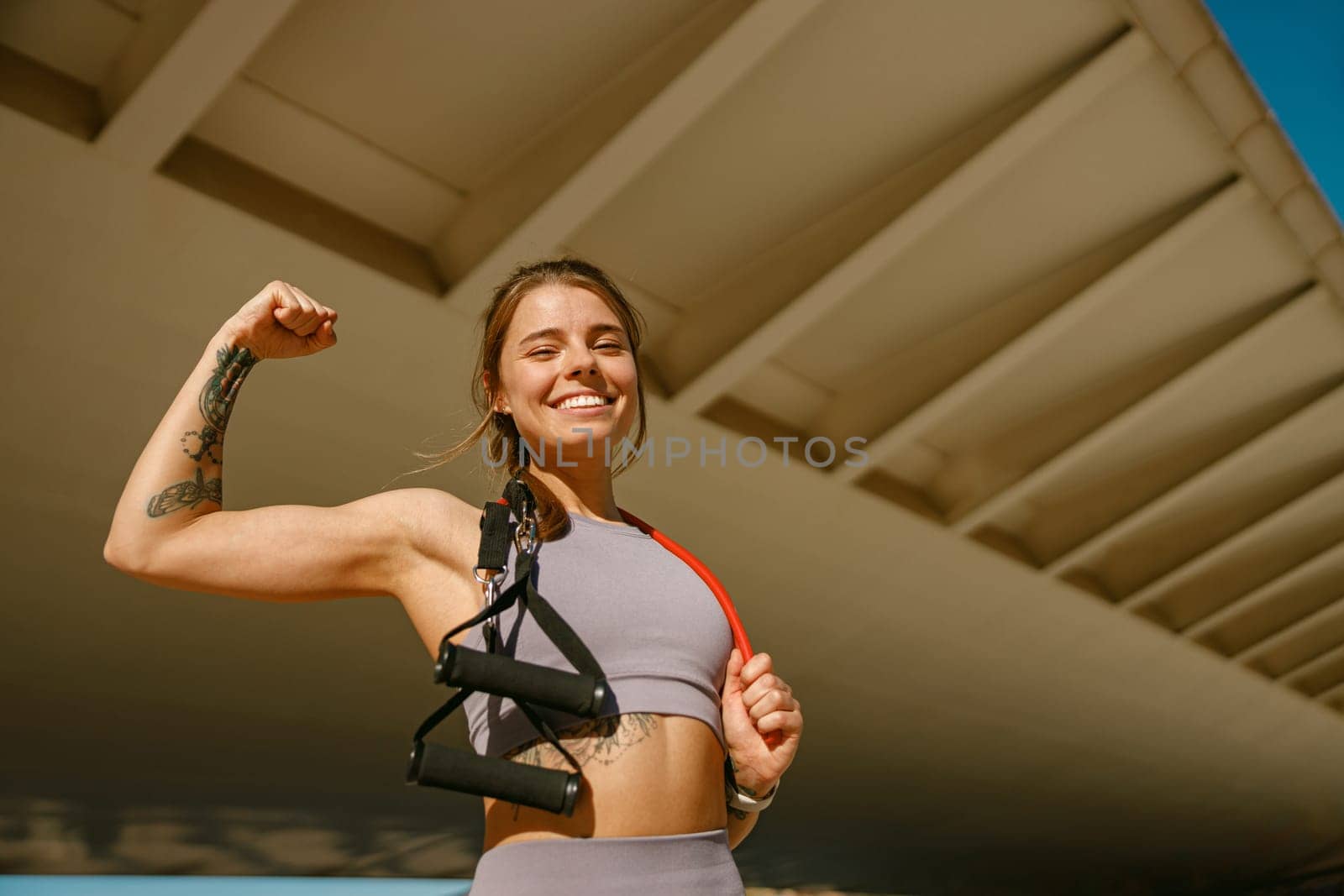 Beautiful athletic woman with a resistance band slung around her neck standing outdoors by Yaroslav_astakhov