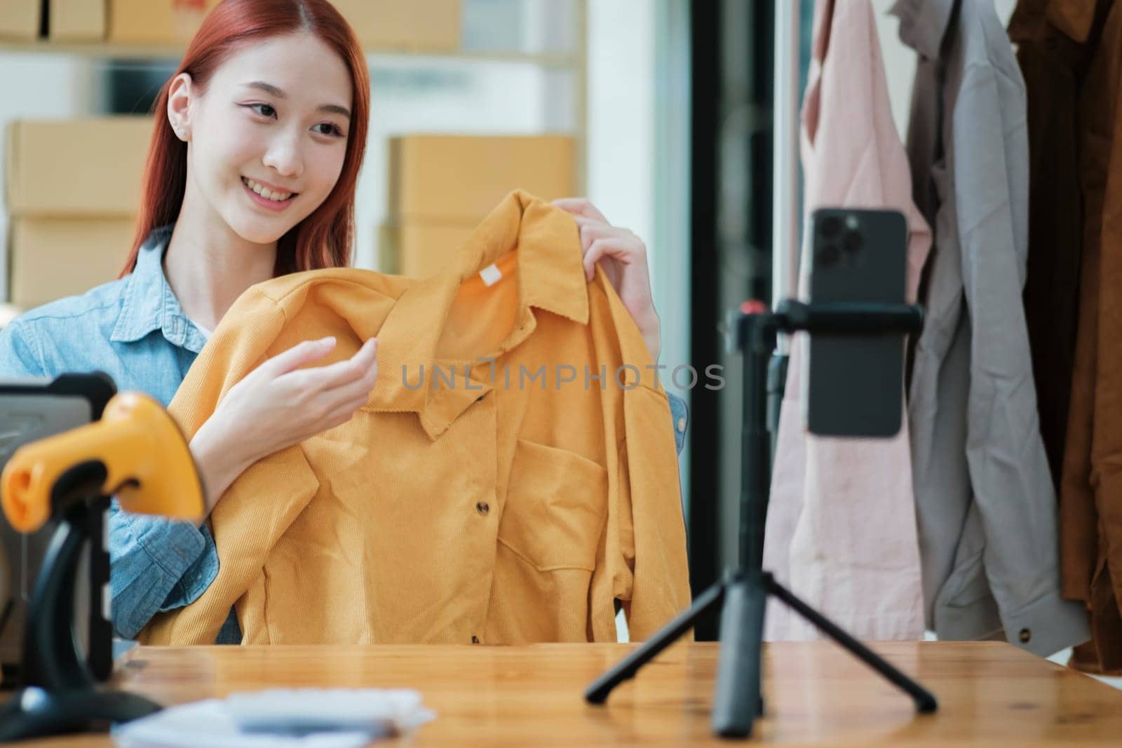 Woman with a social media influence is greeting the audience for recording vlog video live streaming, Lift the postage box during the live show to confirm the customer's order, Online fashion clothing