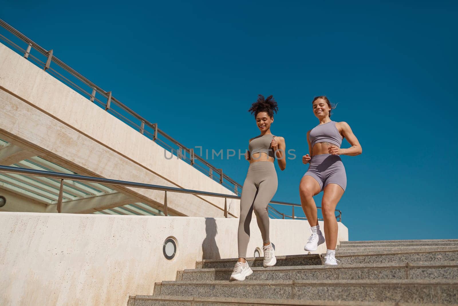 Young athletic women in sportswear are jogging around the city in early morning. Reaching the goal by Yaroslav_astakhov