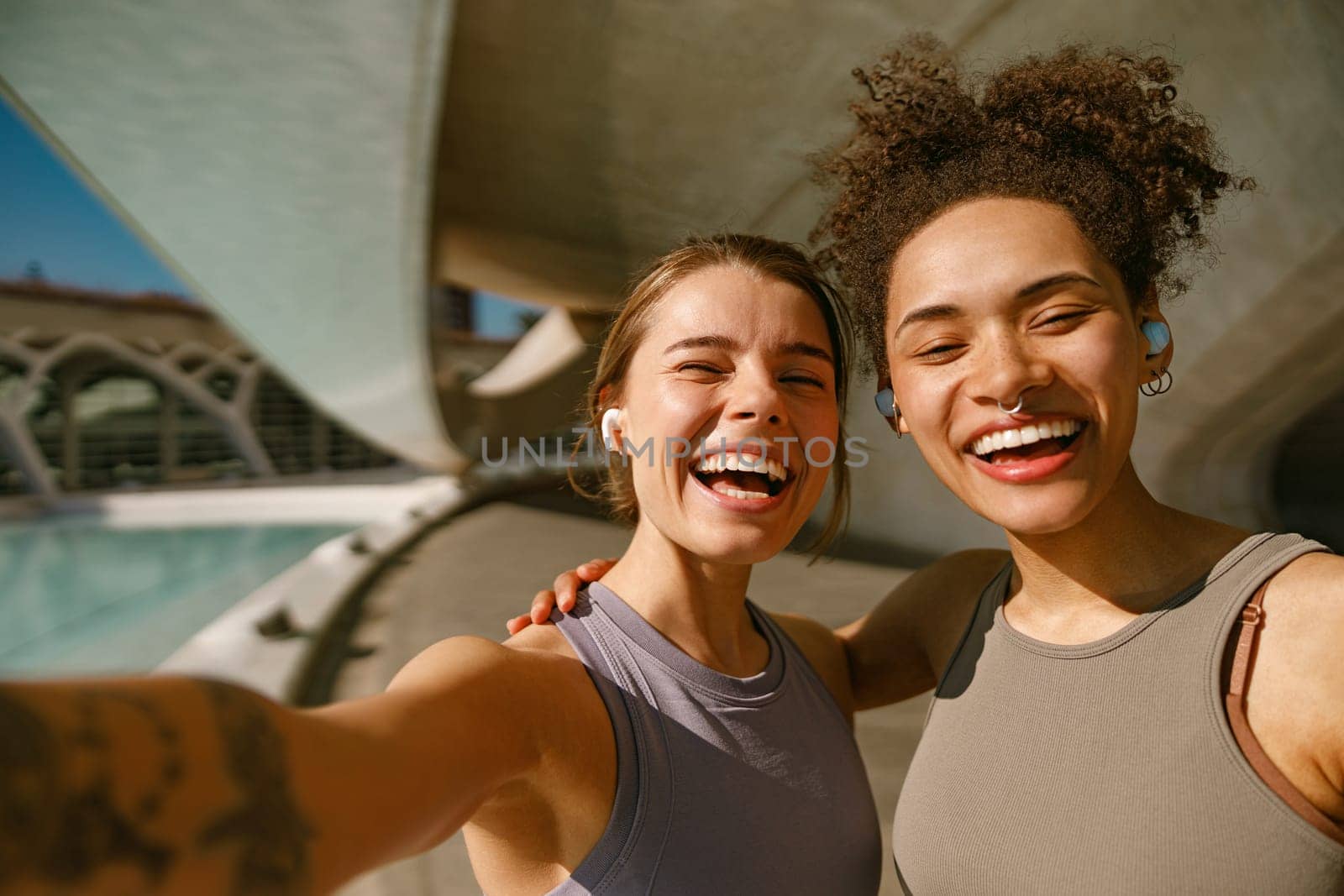 Two young female sportswomen have a rest after morning jogging outdoors. High quality photo