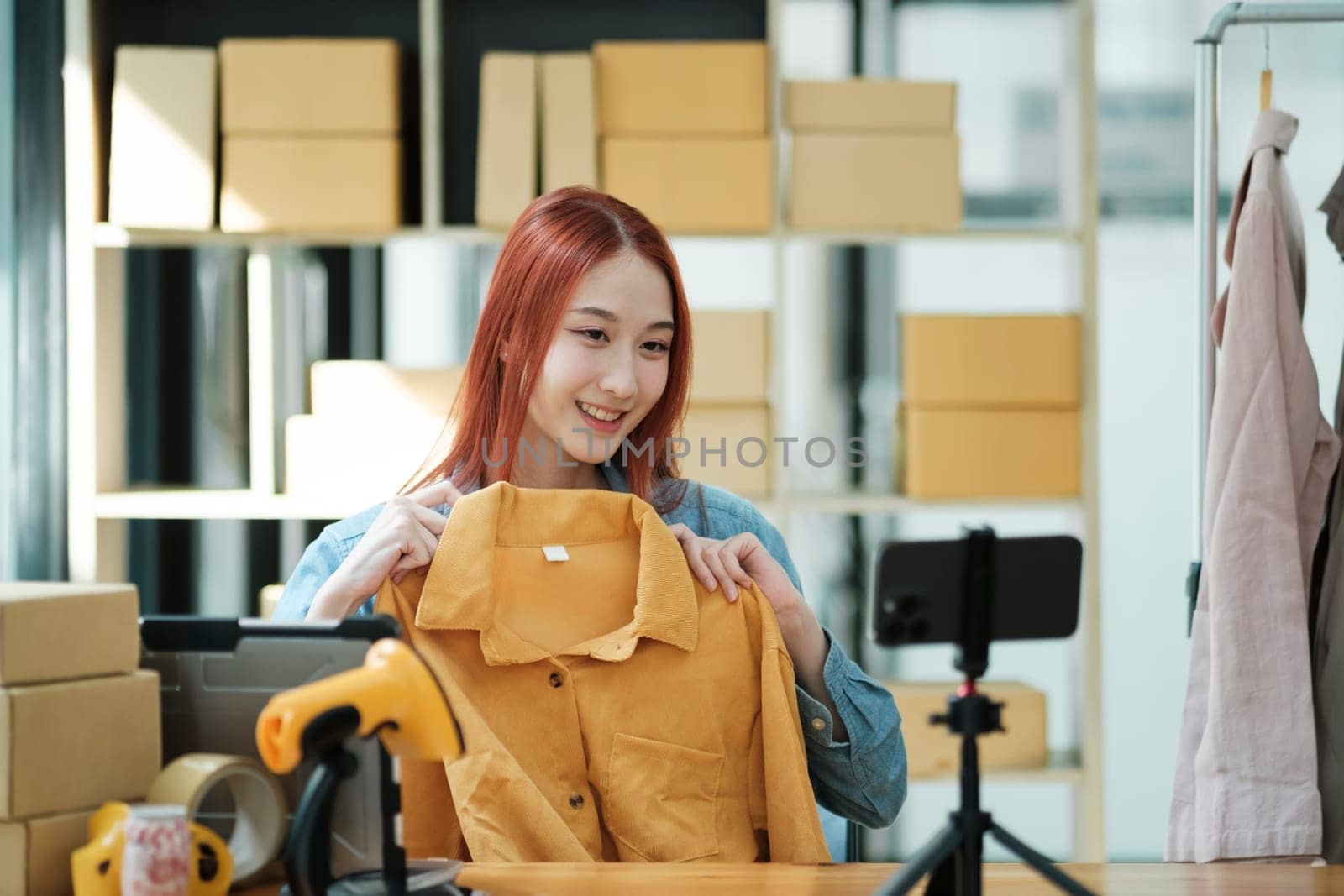 Woman with a social media influence is greeting the audience for recording vlog video live streaming, Lift the postage box during the live show to confirm the customer's order, Online fashion clothing.