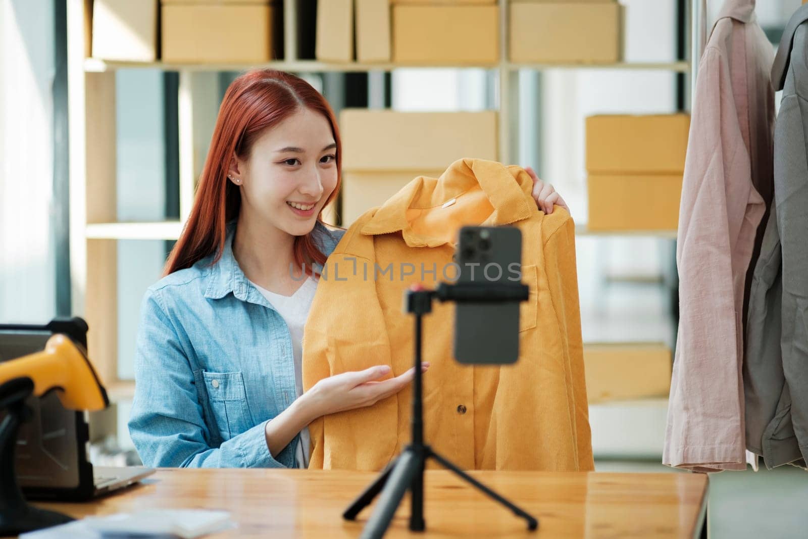 Woman with a social media influence is greeting the audience for recording vlog video live streaming, Lift the postage box during the live show to confirm the customer's order, Online fashion clothing