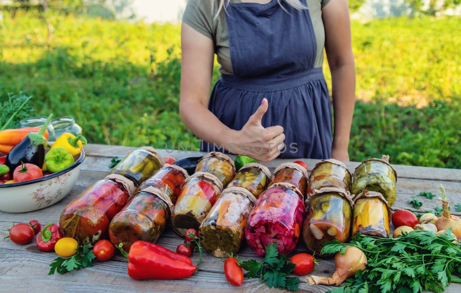 Woman canning vegetables in jars on the background of nature. preparations for the winter.