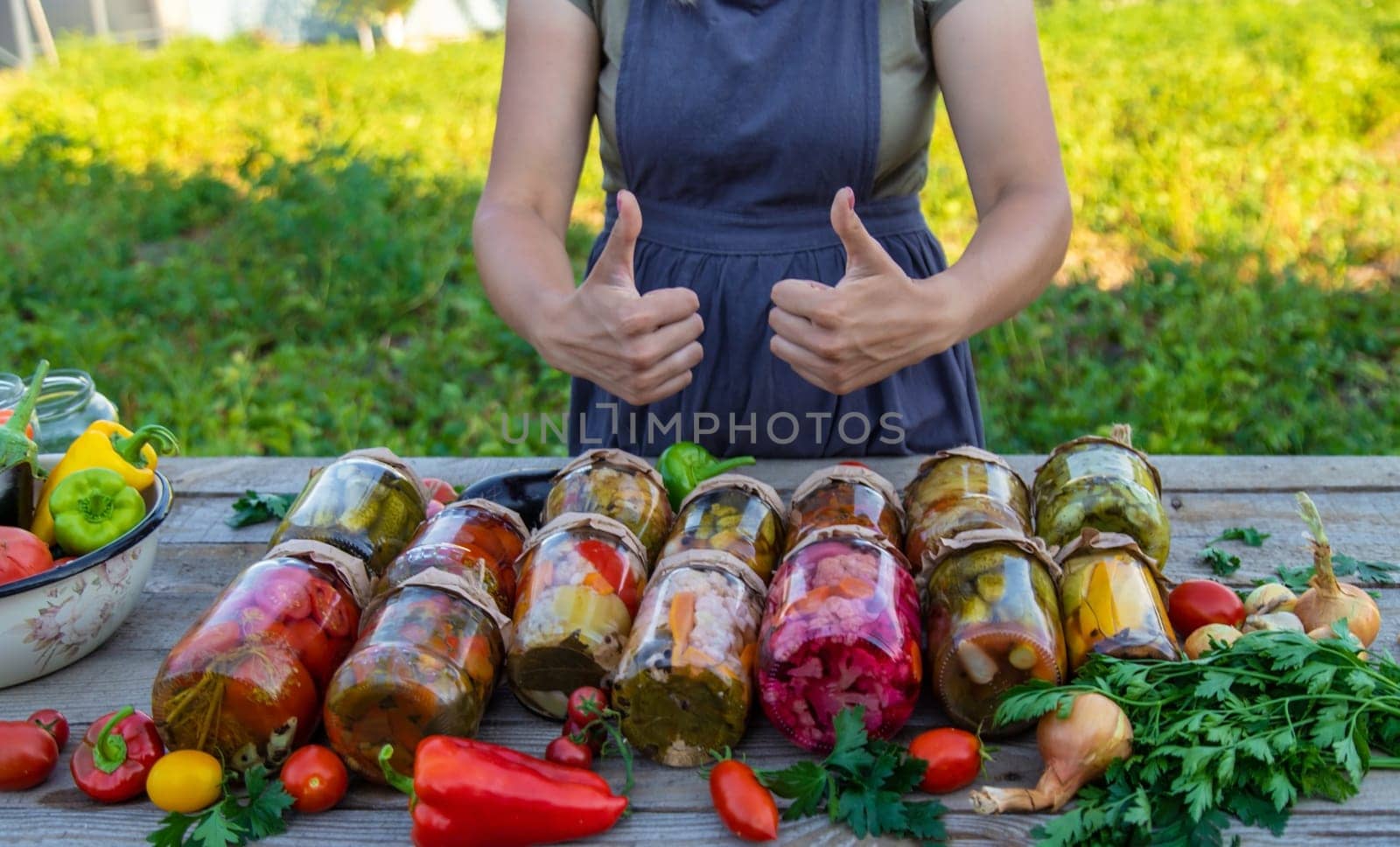 Woman canning vegetables in jars on the background of nature. preparations for the winter.