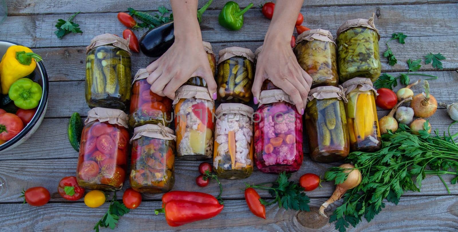 Woman canning vegetables in jars on the background of nature. preparations for the winter.