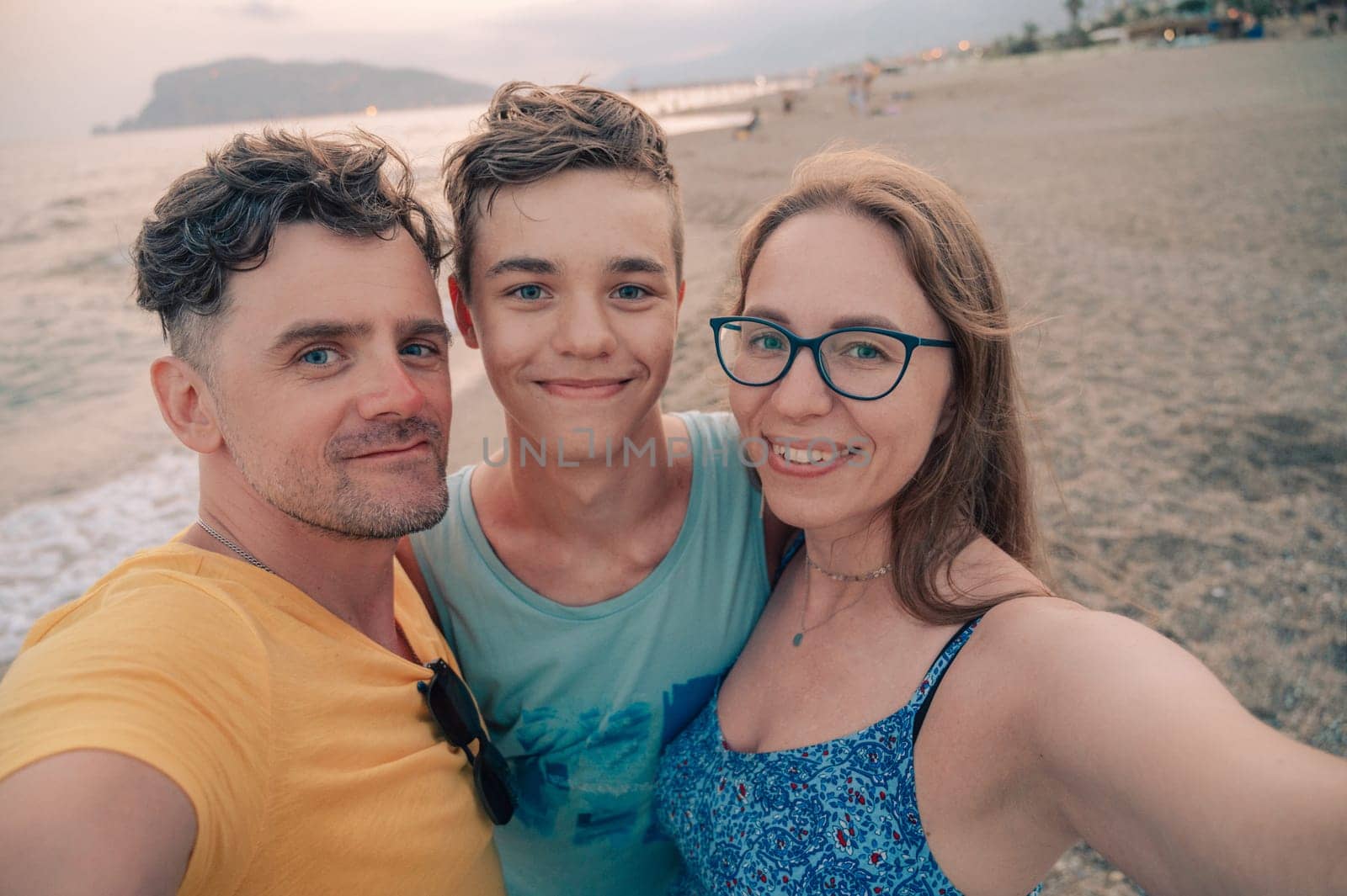 Happy family taking a photo on a beach at the sea in Alanya city, Turkey. Travelling or vacation concept